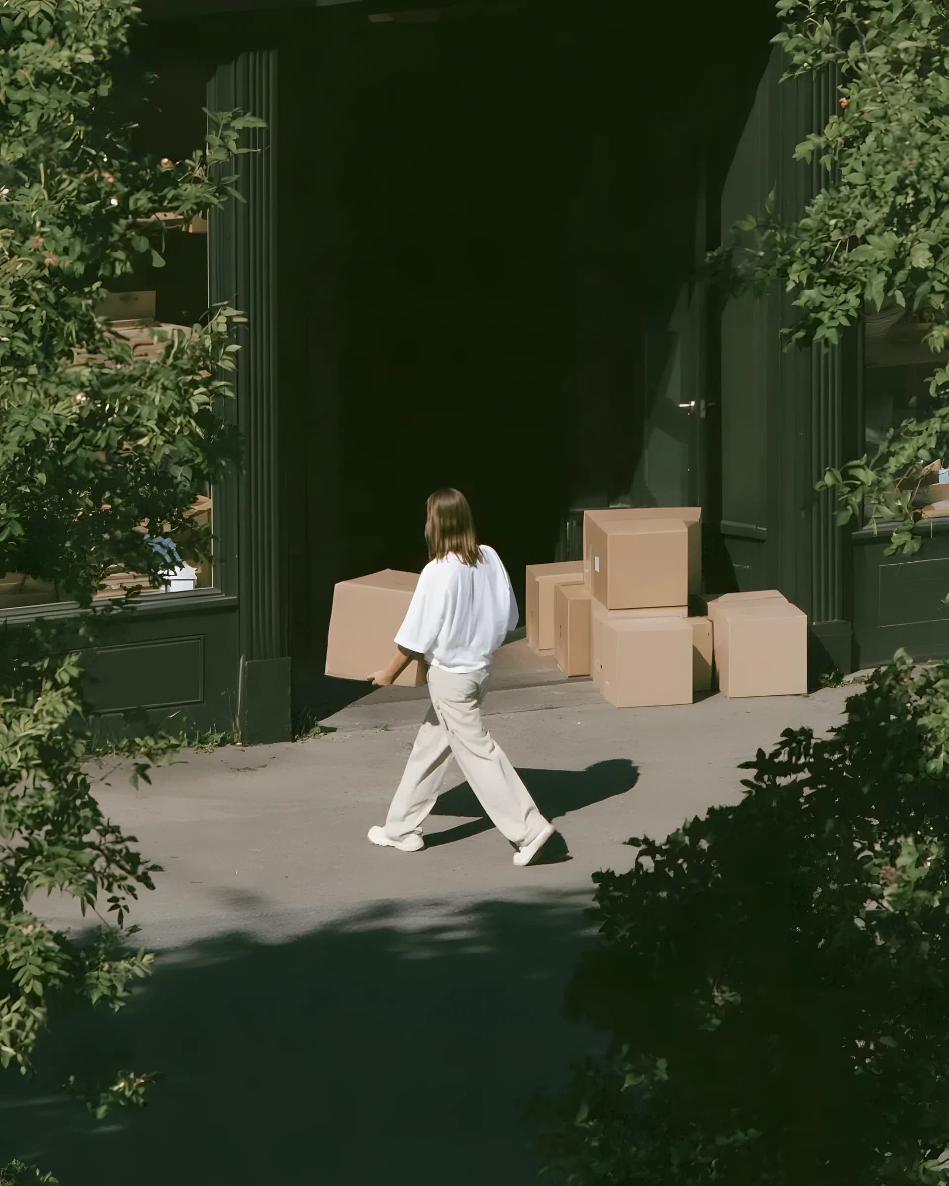 a worker carrying a box into a shaded loading doorway