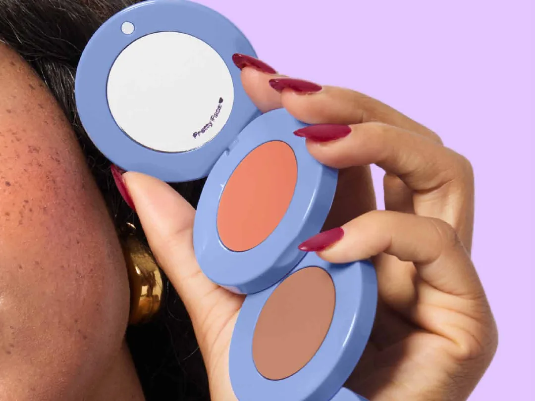 A hand fanning out Alleyoop's three-pan compact against a lilac background.