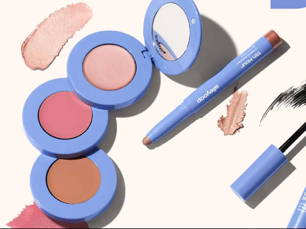 Alleyoop products on a cream background: a stacked compact of blush, bronzer and highlighter pans, an eyeshadow stick and a mascara, all in Alleyoop's periwinkle blue.