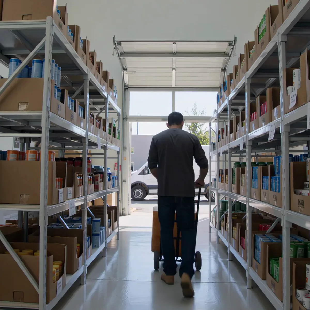 a worker wheeling stock toward an open loading bay